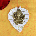 Elegant white leaf-shaped wall hanging featuring a serene idol of Lord Ganesh, ideal for enhancing spiritual ambiance and home decoration. India’s Largest Pooja Accessories Brand – www.satvikstore.in